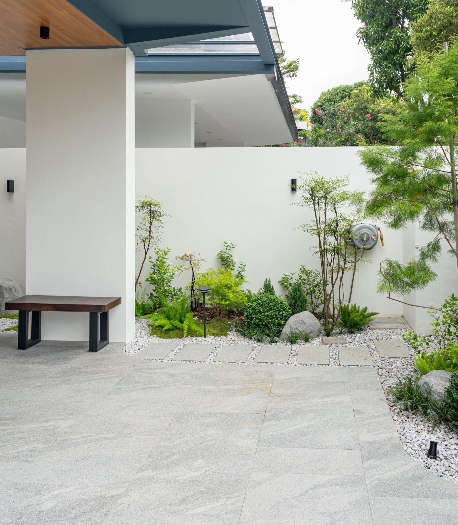 Layered planting, pale gravel and boulders bordering the forecourt at Chiap Guan Avenue.