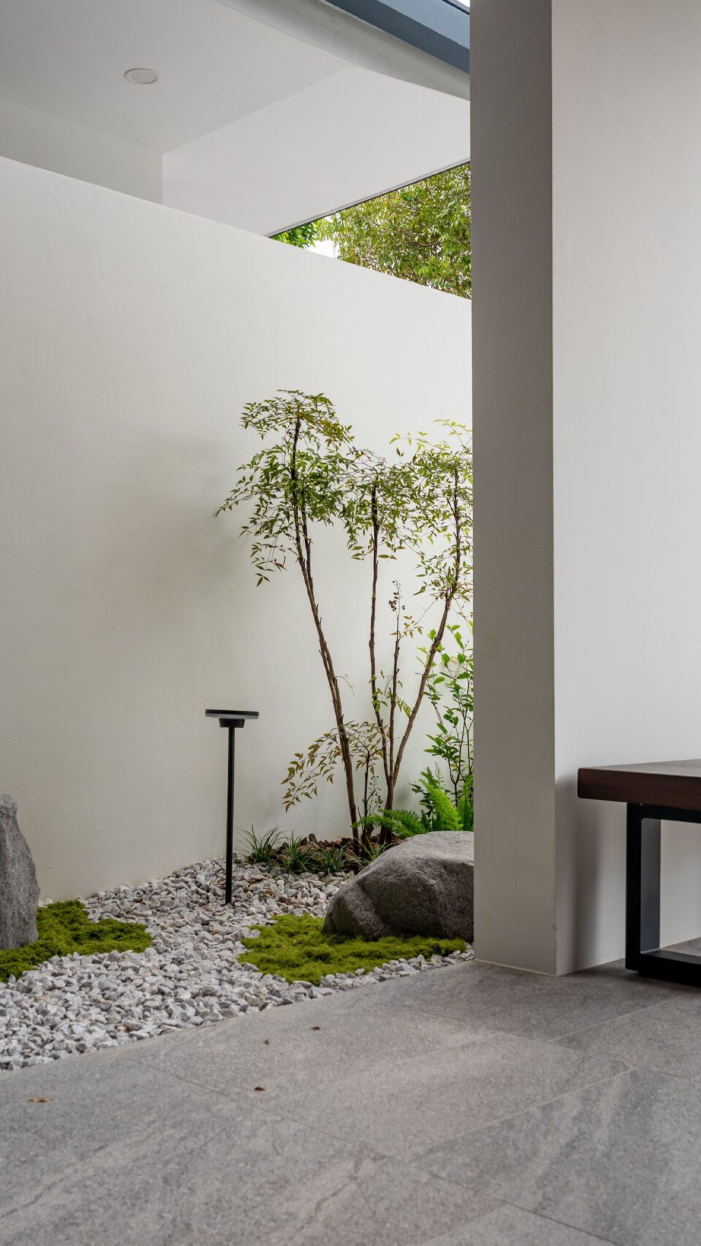 Boulders set within green groundcover and pale gravel beside the sheltered porch.