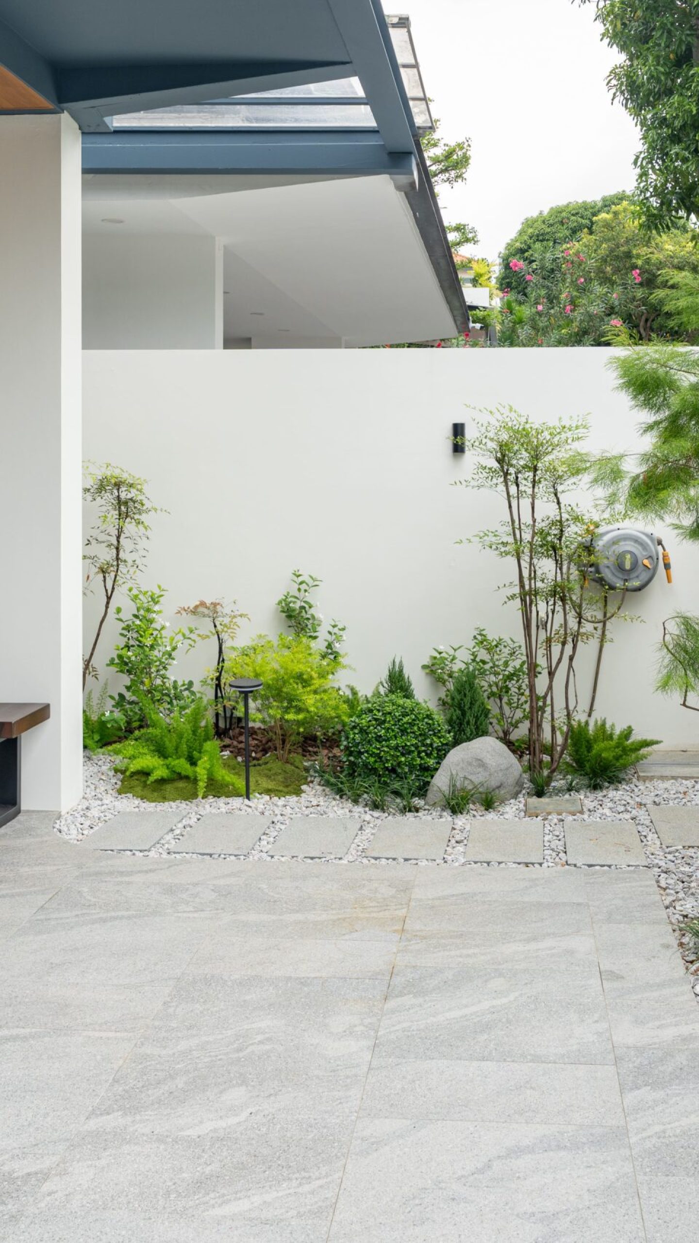 Layered planting, pale gravel and boulders bordering the forecourt at Chiap Guan Avenue.