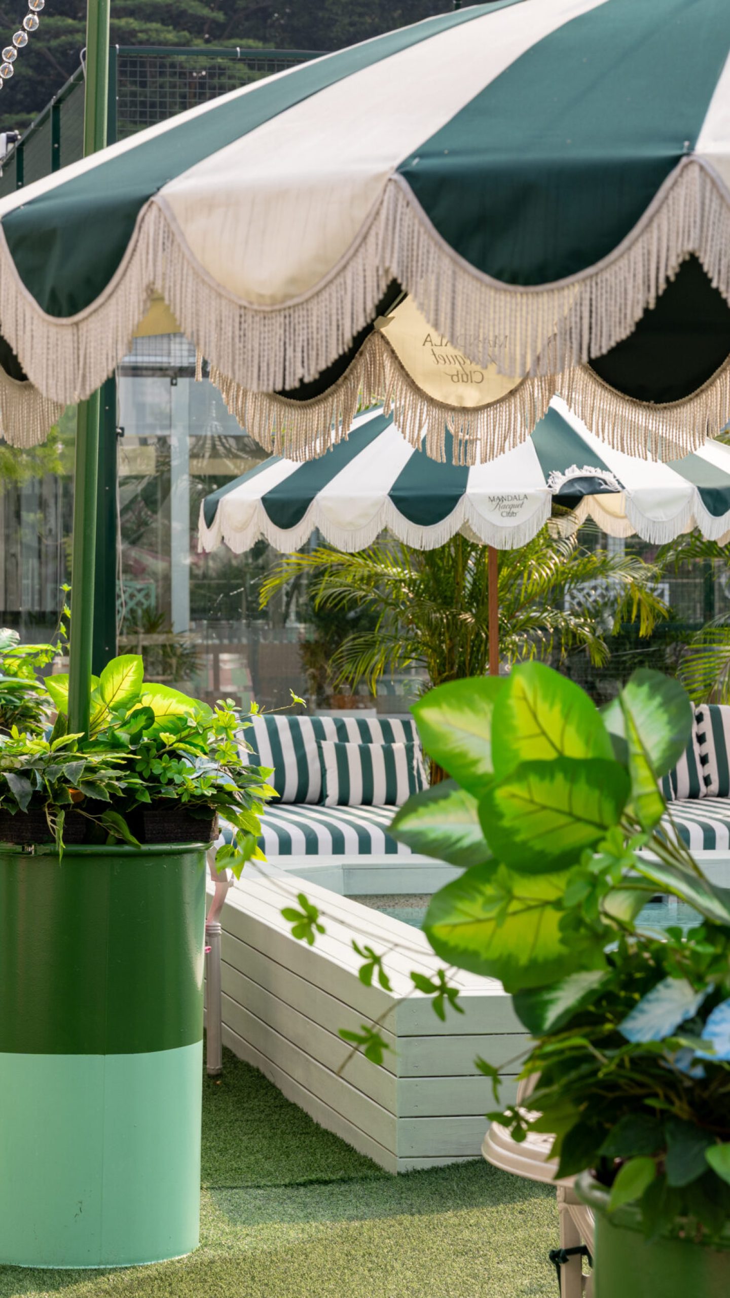Mixed foliage arrangements in green-and-mint planters beside the poolside seating.
